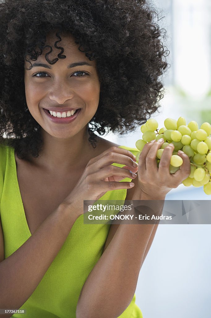 Portrait of a smiling woman eating grapes