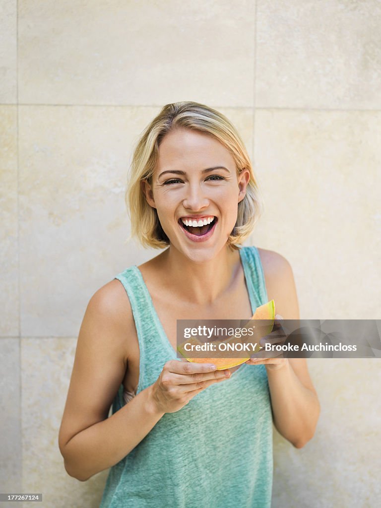 Smiling woman eating melon