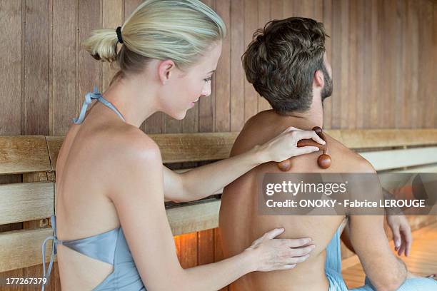 woman massaging on her friend's back with a massager in a sauna - girlfriend massage ストックフォトと画像