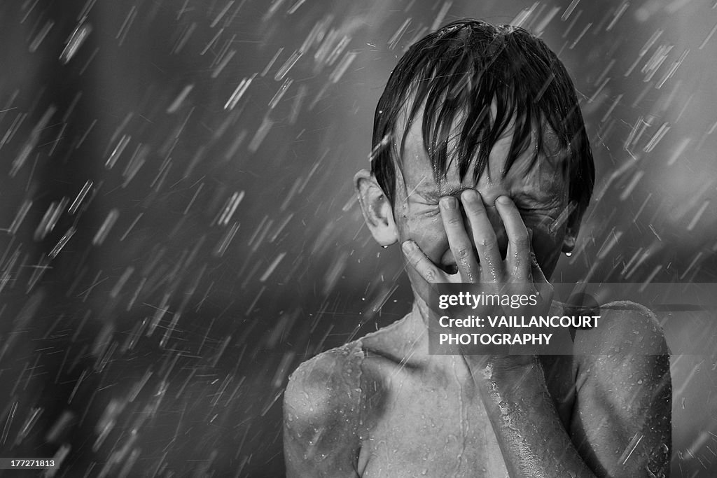 Boy playing in the sprinklers on a hot summer day