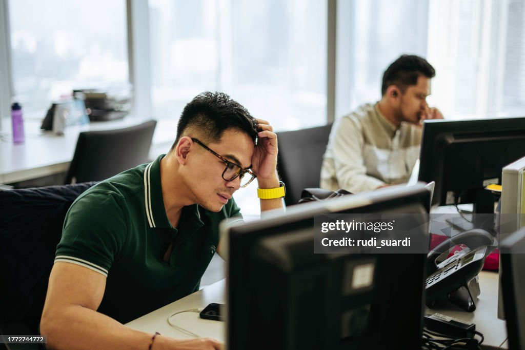 Plan d’un jeune homme d’affaires qui a l’air stressé tout en travaillant dans un bureau moderne