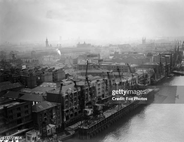 High-angle view of a wharf, cranes and warehouses on the River Thames in London, England, 1928. The view was taken from Tower Bridge.