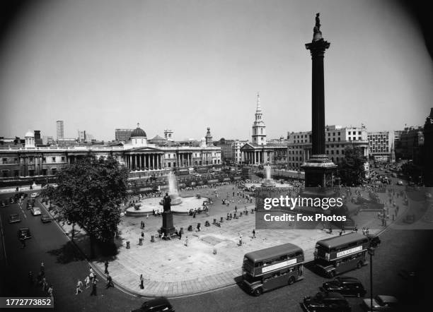 High-angle view of double-decker buses among traffic around Trafalgar Square, with Nelson's Column, a granite Corinthian column surmounted by a...