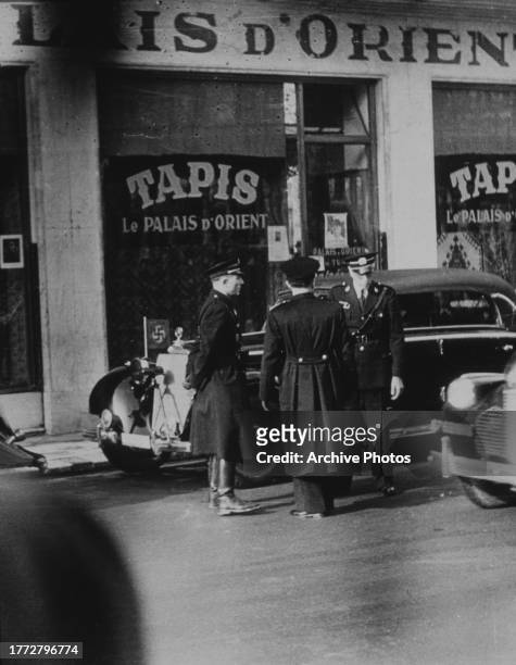 Three officers of Pierre Laval's Nazi militia, the so-called 'French Militia', guarding the car of German ambassador Otto Abetz, in France, circa...