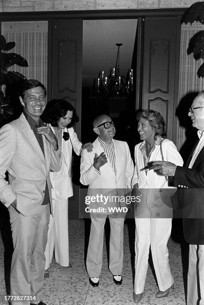 Louis Jourdan, Audrey Wilder, Irving "Swifty" Lazar, Berthe Jourdan, and Billy Wilder attend a party at the Lazar residence in Los Angeles,...