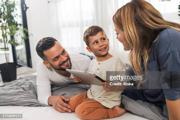 kleiner junge mit tablet im bett - boy in pajamas and mom on tablet stock-fotos und bilder