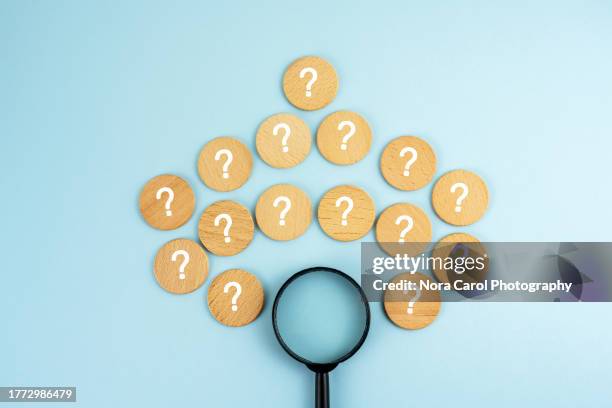 question marks and magnifying glass on blue background - punctuation mark stock pictures, royalty-free photos & images