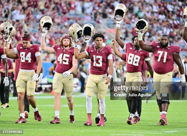 Jordan Travis of the Florida State Seminoles raises his helmet with teammates prior to a game against the LSU Tigers at Camping World Stadium on...