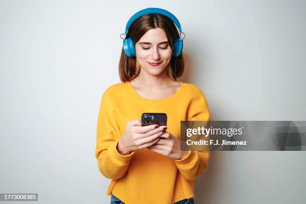 woman dressed in yellow using mobile phone on white background - earbuds isolated stock pictures, royalty-free photos & images