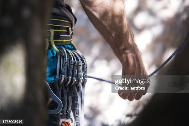 athletic man climb rock with rope and carabiners, lead climbing. row of carabiners in a climb harness. - karabiner stock pictures, royalty-free photos & images