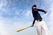 baseball player taking a swing with cloud background