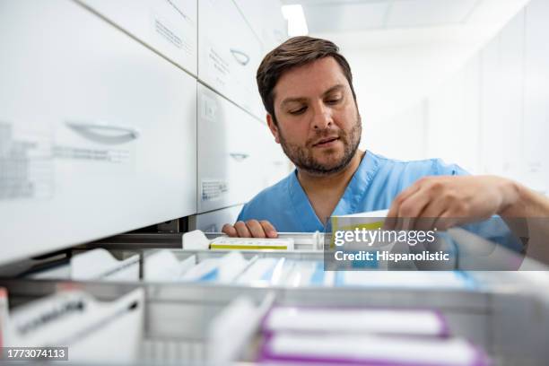 nurse searching for medicines at the hospital pharmacy - kabinet dokter stockfoto's en -beelden