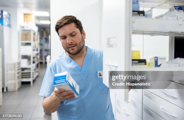 doctor picking up some medicines at the hospital pharmacy - kabinet dokter stockfoto's en -beelden