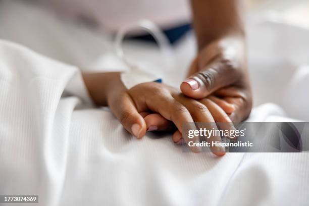 nahaufnahme einer mutter, die im krankenhaus die hand ihrer tochter hält - notaufnahme stock-fotos und bilder