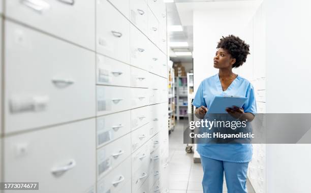 nurse taking inventory of the medicines at the hospital pharmacy - kabinet dokter stockfoto's en -beelden