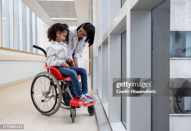 doctor talking to a girl with cerebral palsy in a wheelchair at the hospital - hydrocephalus stock pictures, royalty-free photos & images