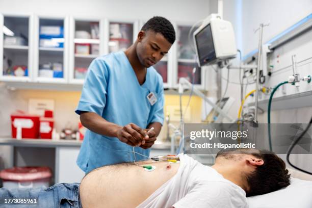 man arriving to the emergency room and nurse placing electrodes - electrode stock pictures, royalty-free photos & images
