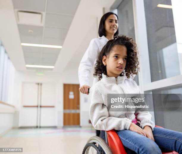 doctor pushing a girl with cerebral palsy in a wheelchair at the hospital - hydrocephalus stock pictures, royalty-free photos & images