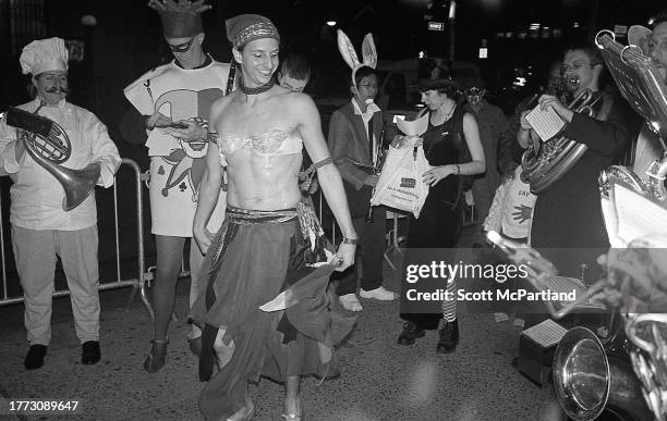 View of various costumed people, include one dressed a chef, one as a harlequin, and one in a headscarf and tasseled bra during the 30th annual...