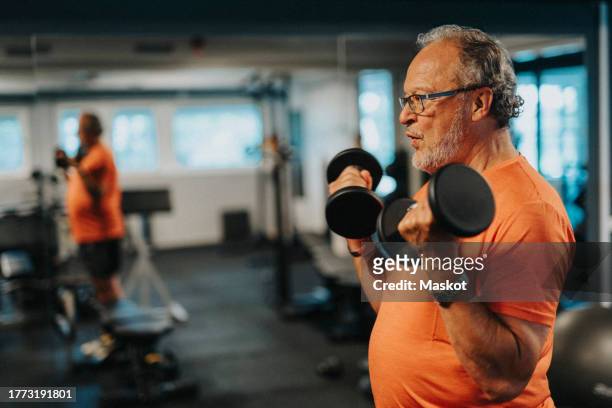 side view of active senior man with dumbbells exercising at health club - health club 個照片及圖片檔