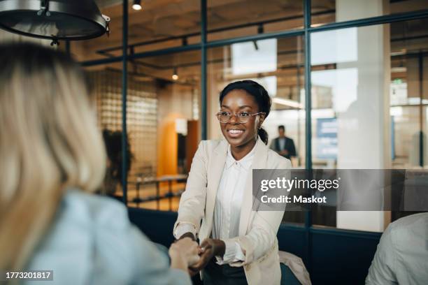 smiling female client shaking hand with businesswoman after meeting at workplace - customer stock pictures, royalty-free photos & images