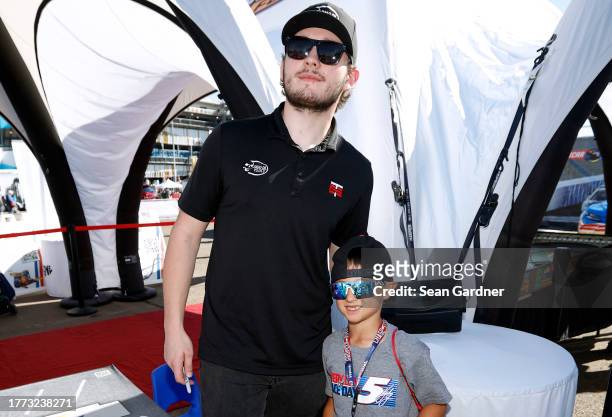 Craftsman Truck Series driver, Taylor Gray pose for photos with a young NASCAR fan during an appearance at the NASCAR Kids Zone on the midway at...