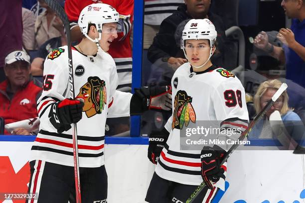 Kevin Korchinski of the Chicago Blackhawks, left, congratulates Connor Bedard on his second goal against the Tampa Bay Lightning during the first...