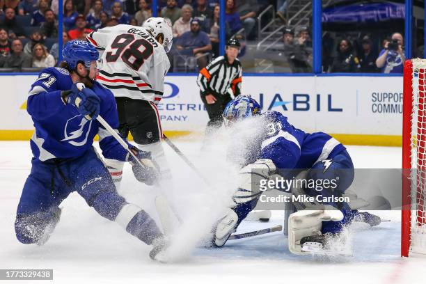 Connor Bedard of the Chicago Blackhawks scores past Jonas Johansson of the Tampa Bay Lightning as Anthony Cirelli defends during the first period at...