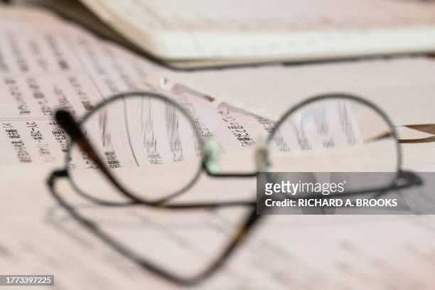 This photo taken on September 5, 2023 shows the glasses of chief Buddhist priest Eiichi Shinohara sitting on documents, during an interview with AFP...