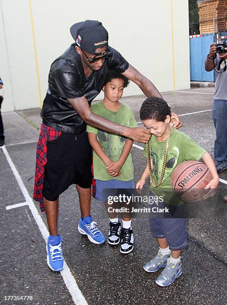 Fabolous lets a young fan try on his gold necklace during EBC's "The Finale" Tournament for the Reebok Question Mid Draft Pick Release at Rucker Park...