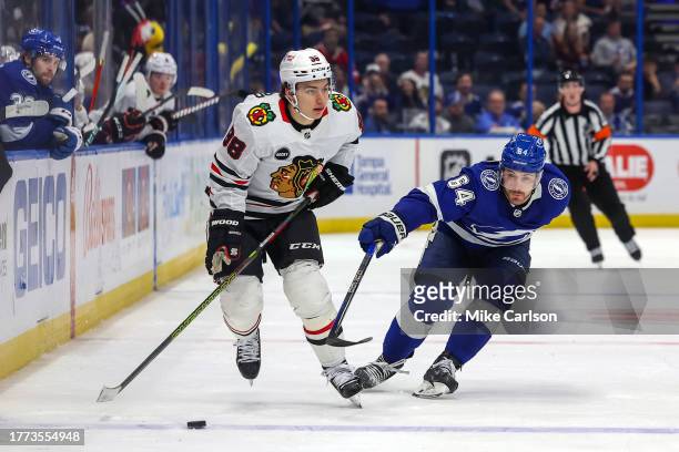 Connor Bedard of the Chicago Blackhawks brings the puck up the ice past Tyler Motte of the Tampa Bay Lightning during the third period at the Amalie...