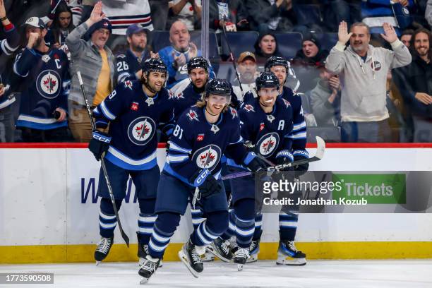 Kyle Connor of the Winnipeg Jets is all smiles as he leads teammates Alex Iafallo, Dylan DeMelo, Mark Scheifele and Josh Morrissey to the bench after...