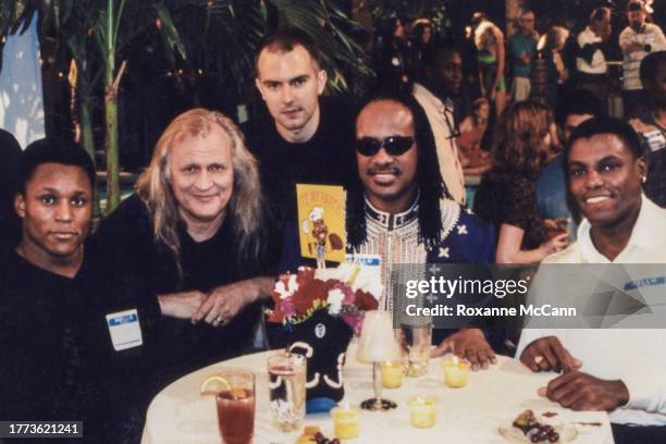 Barry Sanders of the Detroit Lions, Joe Pytka, Stacy Wall of Wieden Kennedy, Stevie Wonder, and runner Carl Lewis sit at a table on the set of the...