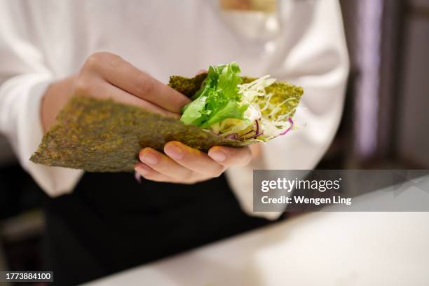 faire des sushis roulés à la main en gros plan - nori photos et images de collection