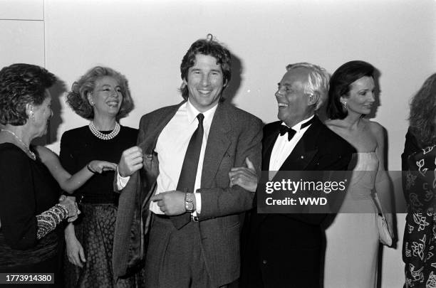 Actor Richard Gere shows designer Giorgio Armani his suit label, as guests watch the exchange, with socialite Lee Radziwill.