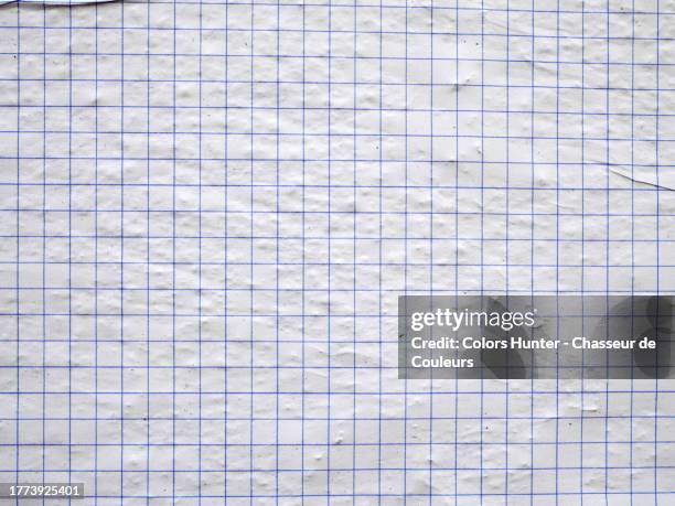 close-up of a sheet of graph paper glued together and on a textured wall in paris - ruitjespapier stockfoto's en -beelden
