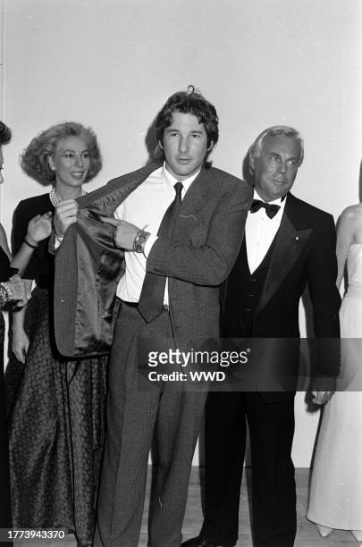 Actor Richard Gere shows designer Giorgio Armani his suit label, as guests watch the exchange.