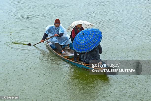 Man rows a boat in the Dal Lake amid rainfall in Srinagar on November 10, 2023.