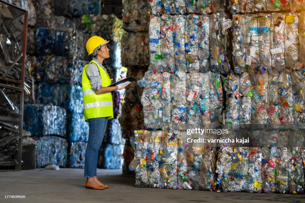 Arbeiterin kontrolliert den Bestand und kontrolliert die Trennung der recycelbaren Abfälle der Kunststoffabfall-Recyclinganlage. Und andere Arten von Abfällen, das Konzept des Recyclings.