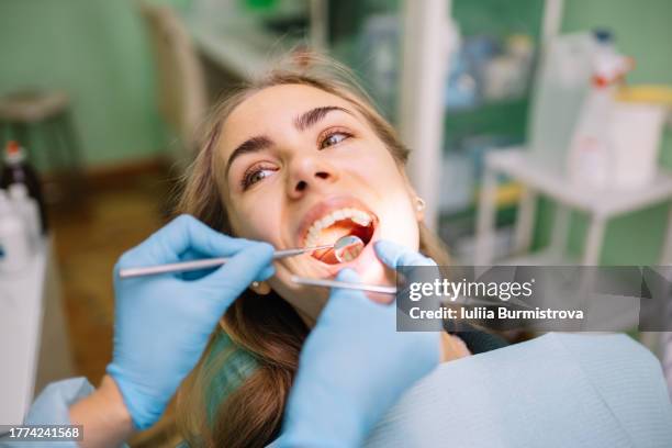 unrecognizable dentist conducts detailed examination of female patient oral health - boca abierta fotografías e imágenes de stock