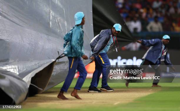 Groundstaff bring on covers as rain delays play during the ICC Men's Cricket World Cup India 2023 between New Zealand and Pakistan at M. Chinnaswamy...