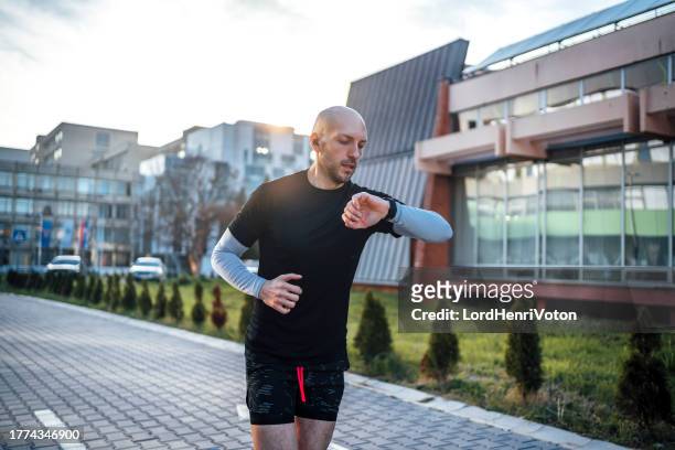 man checks data on a fitness tracker while running - stopwatch stock pictures, royalty-free photos & images
