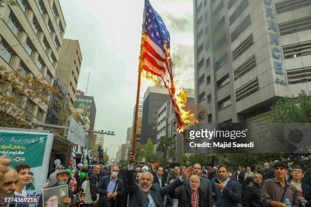 People burn US flag during a rally outside the former US embassy in Tehran, to support the Palestinians of the Gaza Strip and to mark the 44th...