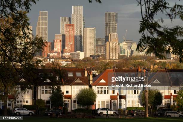 Looking through ash trees towards suburban residential properties and distant city high-rises in Ruskin Park, a public green space in Lambeth, on 9th...