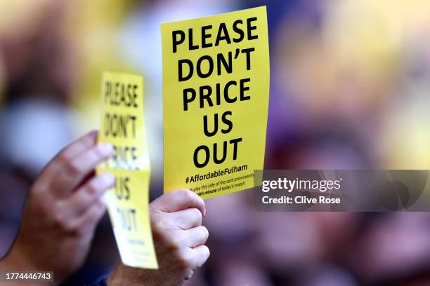 Fans of Fulham hold flyers reading "Please don't price us out" during the Premier League match between Fulham FC and Manchester United at Craven...