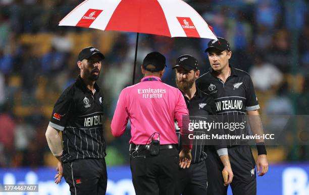 Daryl Mitchell, Kane Williamson and Tim Southee of New Zealand react as rain delays play during the ICC Men's Cricket World Cup India 2023 between...