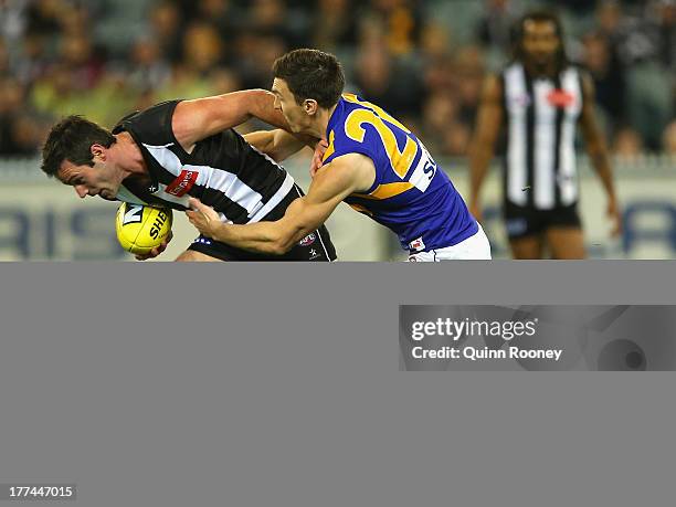 Alan Didak of the Magpies attempts to fend off a tackle by Sam Butler of the Eagles during the round 22 AFL match between the Collingwood Magpies and...