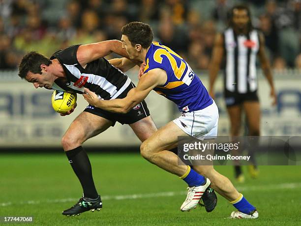 Alan Didak of the Magpies attempts to fend off a tackle by Sam Butler of the Eagles during the round 22 AFL match between the Collingwood Magpies and...