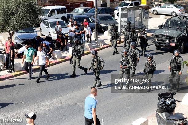 Israeli security forces walks past Muslim men as they take part in Friday Noon prayers in East Jerusalem's neighborhood of Ras al-Amud, on November...