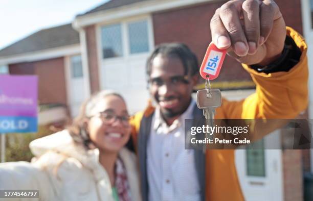 happy couple holding house key outside new home - afro caribbean portrait stock pictures, royalty-free photos & images